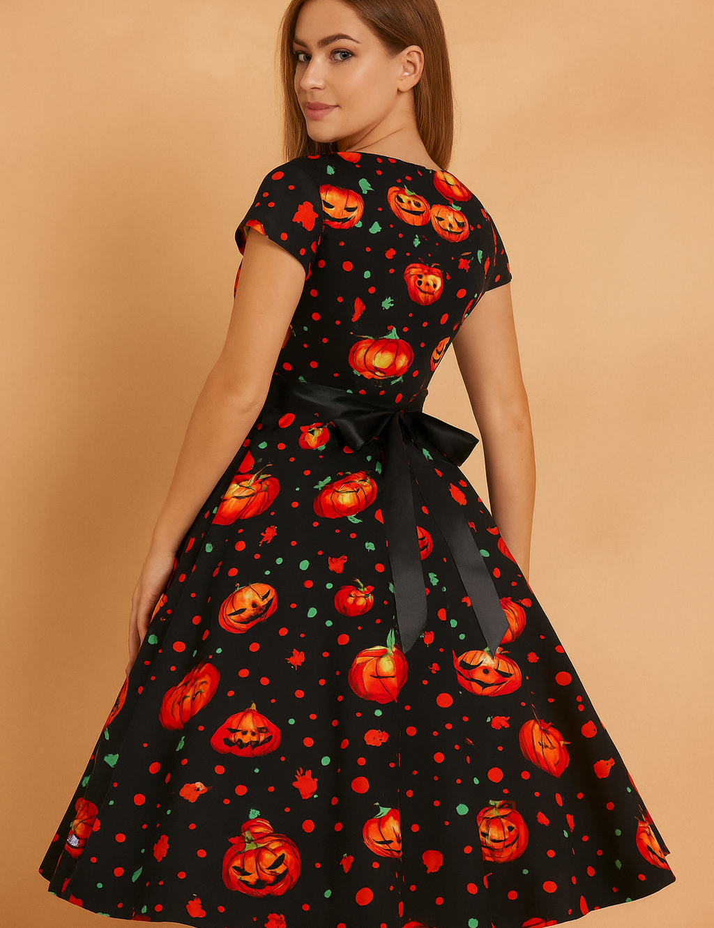 Sukienka Halloweenowa retro z czarnym tłem, ozdobiona intensywnie pomarańczowymi dyniami i zielonymi akcentami, z eleganckim czarnym paskiem w talii i rozkloszowanym dołem.