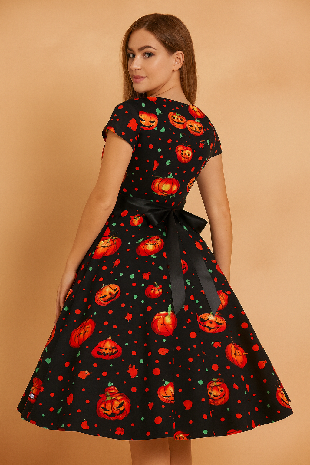 Sukienka Halloweenowa retro z czarnym tłem, ozdobiona intensywnie pomarańczowymi dyniami i zielonymi akcentami, z eleganckim czarnym paskiem w talii i rozkloszowanym dołem.