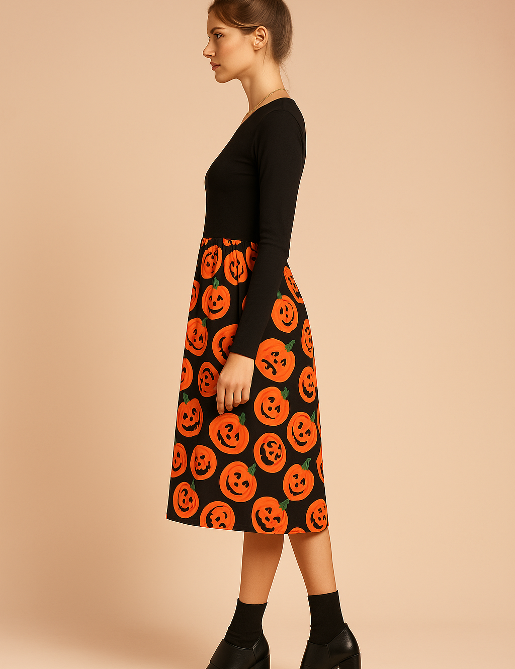 Sukienka halloweenowa z długim rękawem w kolorze czarnym z rozkloszowaną spódnicą midi ozdobioną pomarańczowym nadrukiem dyni z uśmiechniętymi twarzami.