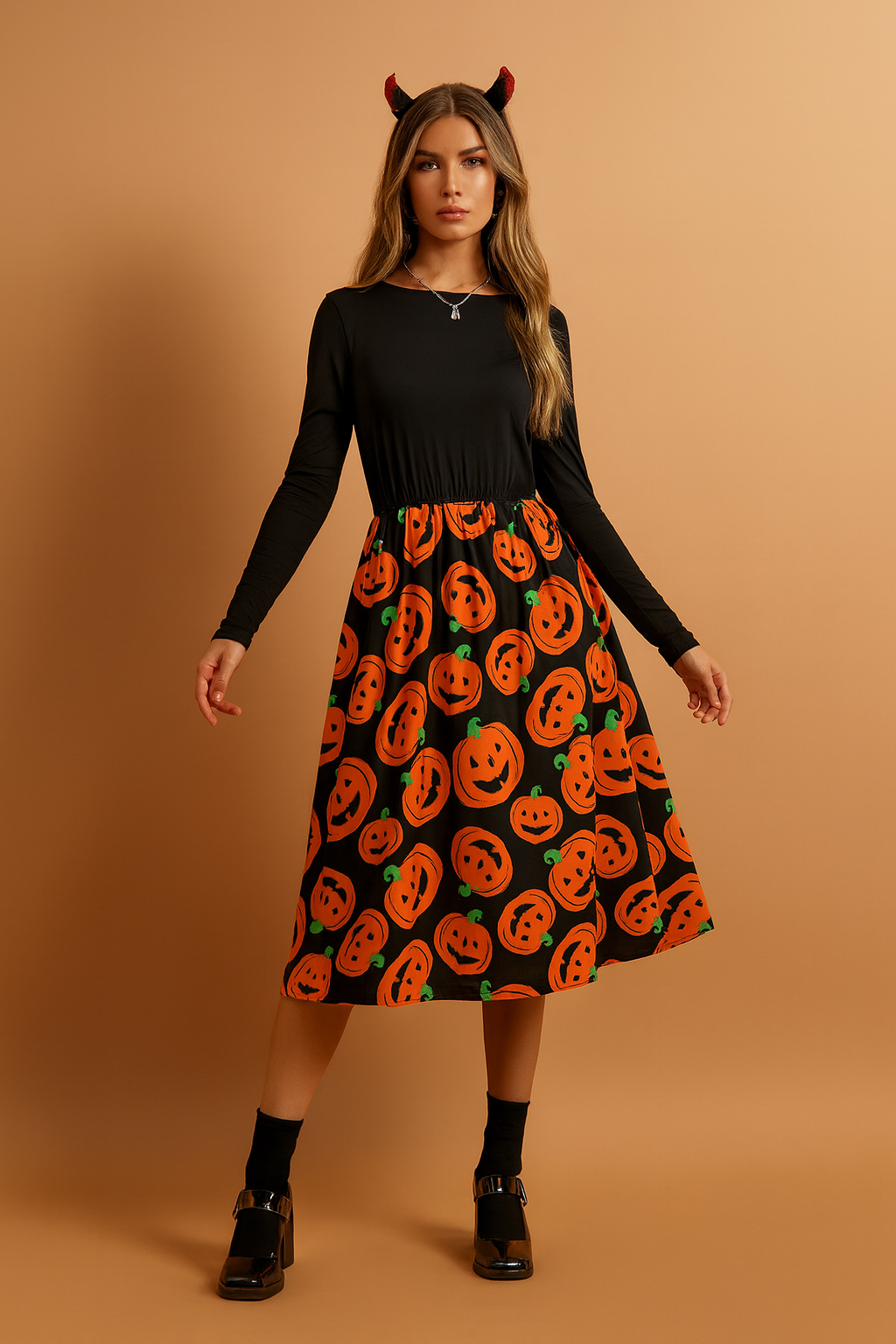 Sukienka halloweenowa z długim rękawem w kolorze czarnym z rozkloszowaną spódnicą midi ozdobioną pomarańczowym nadrukiem dyni z uśmiechniętymi twarzami.
