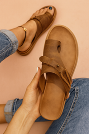 Brown faux leather toe-loop slide sandals featuring a wide distressed strap with a brass rivet detail and matching side cord.