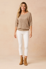 Taupe knit boat-neck sweater with elbow-length sleeves, paired with slim-fit white pants and tan suede ankle boots.