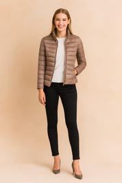 Taupe puffer jacket for women with high collar, horizontal quilted design, zip closure, and slim fit silhouette styled with black pants.