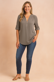 Taupe-gray zip-front blouse with roll-tab sleeves, paired with dark wash skinny jeans and beige block-heel sandals for a polished everyday outfit.