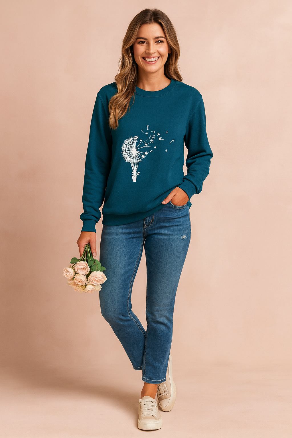 Teal long-sleeve sweatshirt with white dandelion and hot air balloon graphic, paired with fitted blue jeans and beige sneakers.