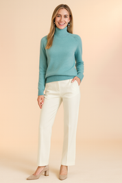 Elegant teal turtleneck sweater paired with tailored white trousers and taupe block-heel pumps, designed for a chic and timeless look.