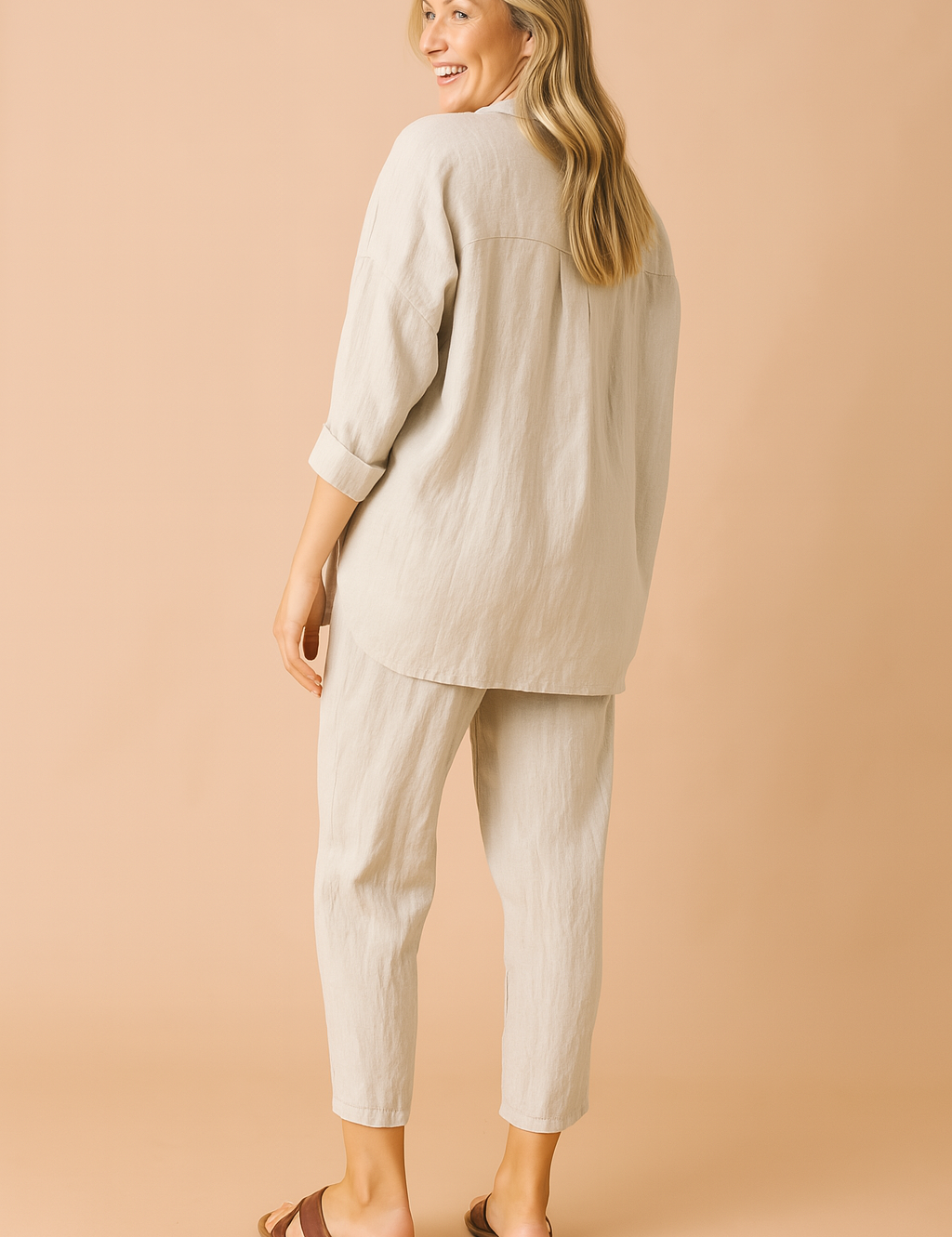 Loose-fit two-piece loungewear set featuring a textured beige weave, composed of a long-sleeved, drop-shoulder button-down top with a curved hem and matching tapered ankle-length pants with subtle vertical creasing for added structure.