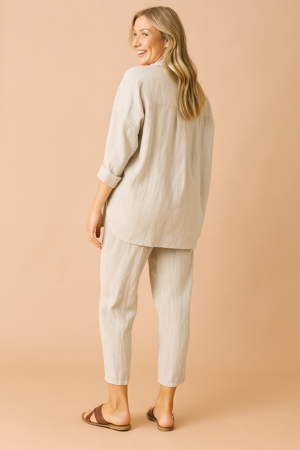 Loose-fit two-piece loungewear set featuring a textured beige weave, composed of a long-sleeved, drop-shoulder button-down top with a curved hem and matching tapered ankle-length pants with subtle vertical creasing for added structure.