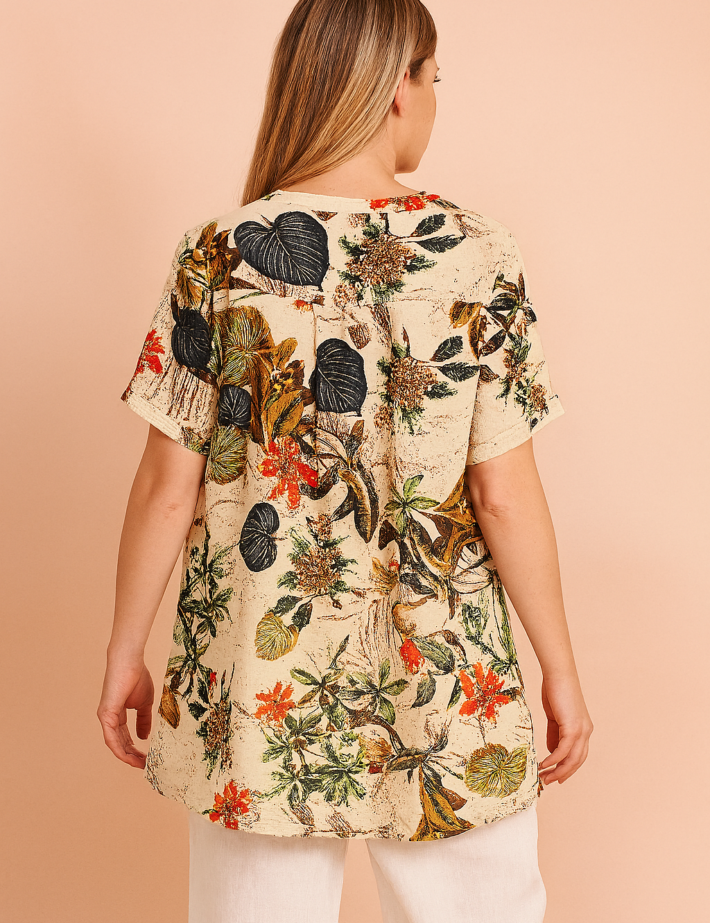 tropical floral tunic top featuring a cream background with vibrant leaf and blossom prints, styled with white linen pants—ideal for casual summer fashion.