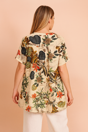 tropical floral tunic top featuring a cream background with vibrant leaf and blossom prints, styled with white linen pants—ideal for casual summer fashion.