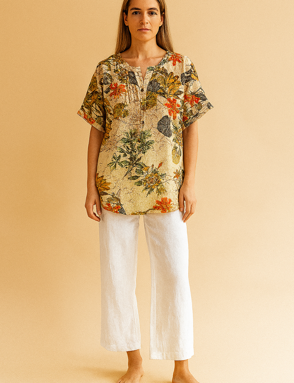 tropical floral tunic top featuring a cream background with vibrant leaf and blossom prints, styled with white linen pants—ideal for casual summer fashion.