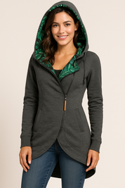 Dark gray asymmetrical zip fleece jacket with curved hem, tropical leaf hood lining, side pockets, and ribbed cuffs, styled with mid-rise blue denim jeans.