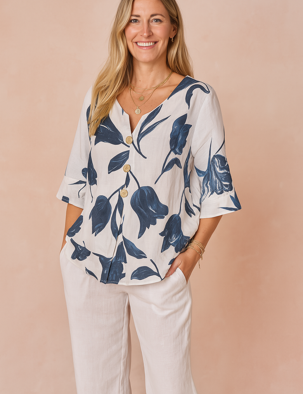 White V-neck button-front blouse with navy blue tulip print, featuring mid-length sleeves and paired with loose-fitting white pants.