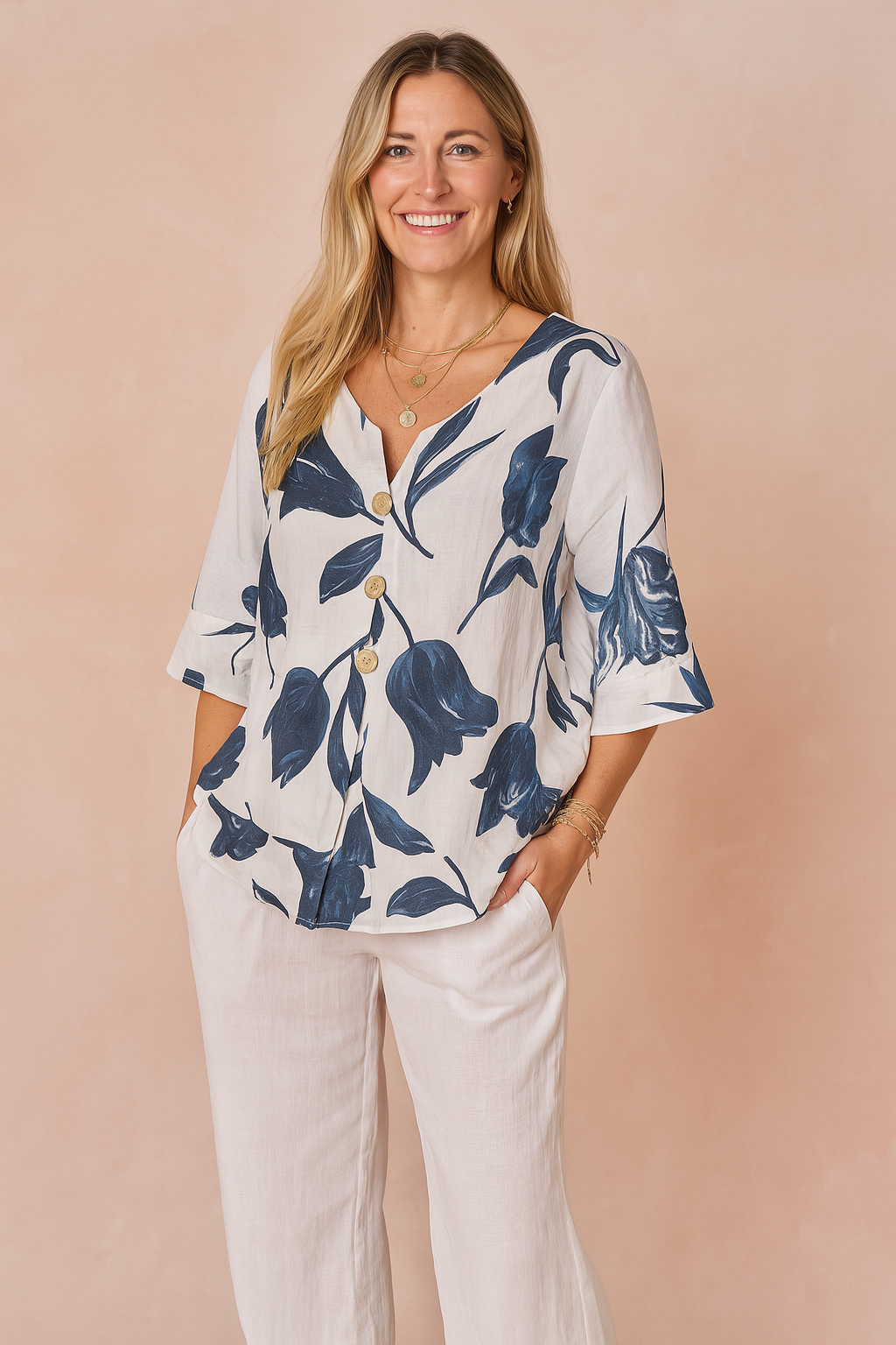 White V-neck button-front blouse with navy blue tulip print, featuring mid-length sleeves and paired with loose-fitting white pants.