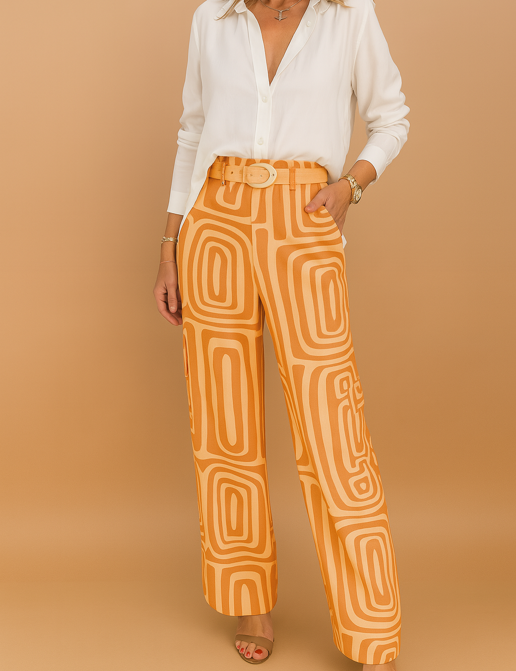 White button-up blouse paired with high-waisted wide-leg orange pants featuring a bold geometric print and matching fabric belt, styled with open-toe heels.