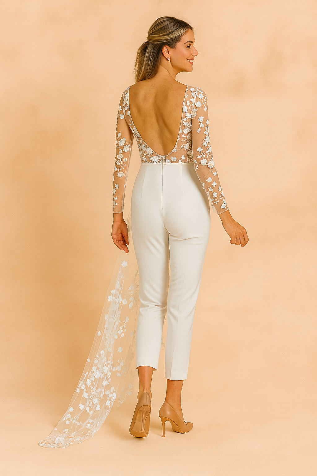 Elegant white bridal jumpsuit with sheer long sleeves, floral lace embroidery, and a flowing tulle train featuring delicate flower appliqué details.