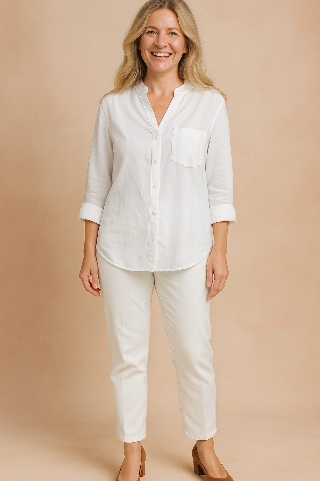 Crisp white long-sleeve linen blouse with rolled cuffs, front chest pocket, and button-down design, styled with tailored white pants and brown block-heel shoes.