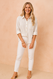 Classic white textured button-up shirt with rolled sleeves, chest pocket detail, and gold buttons, paired with slim-fit white trousers for a polished monochrome look.