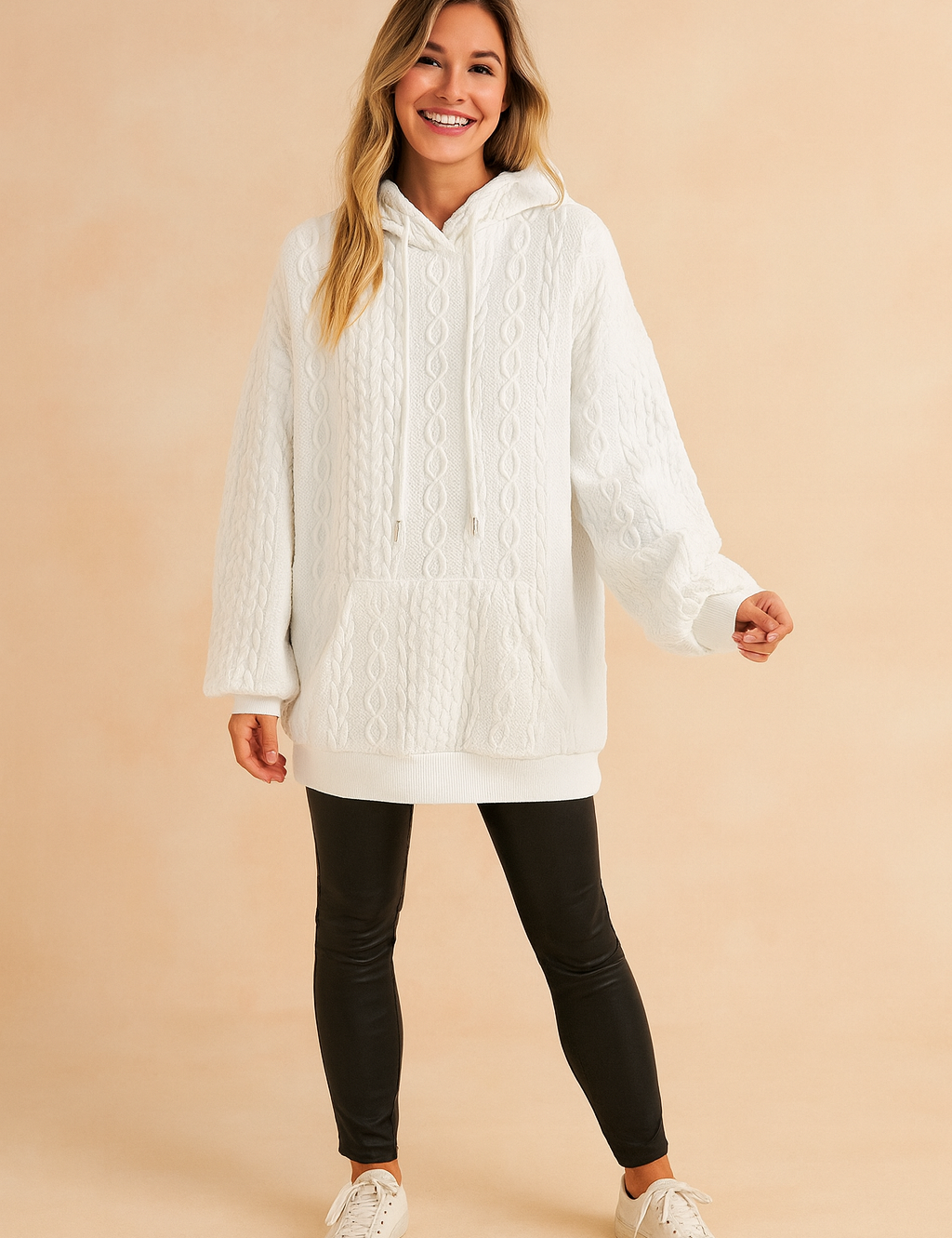 White cable knit hoodie with kangaroo pocket and drawstring, paired with black fitted pants and casual sneakers.