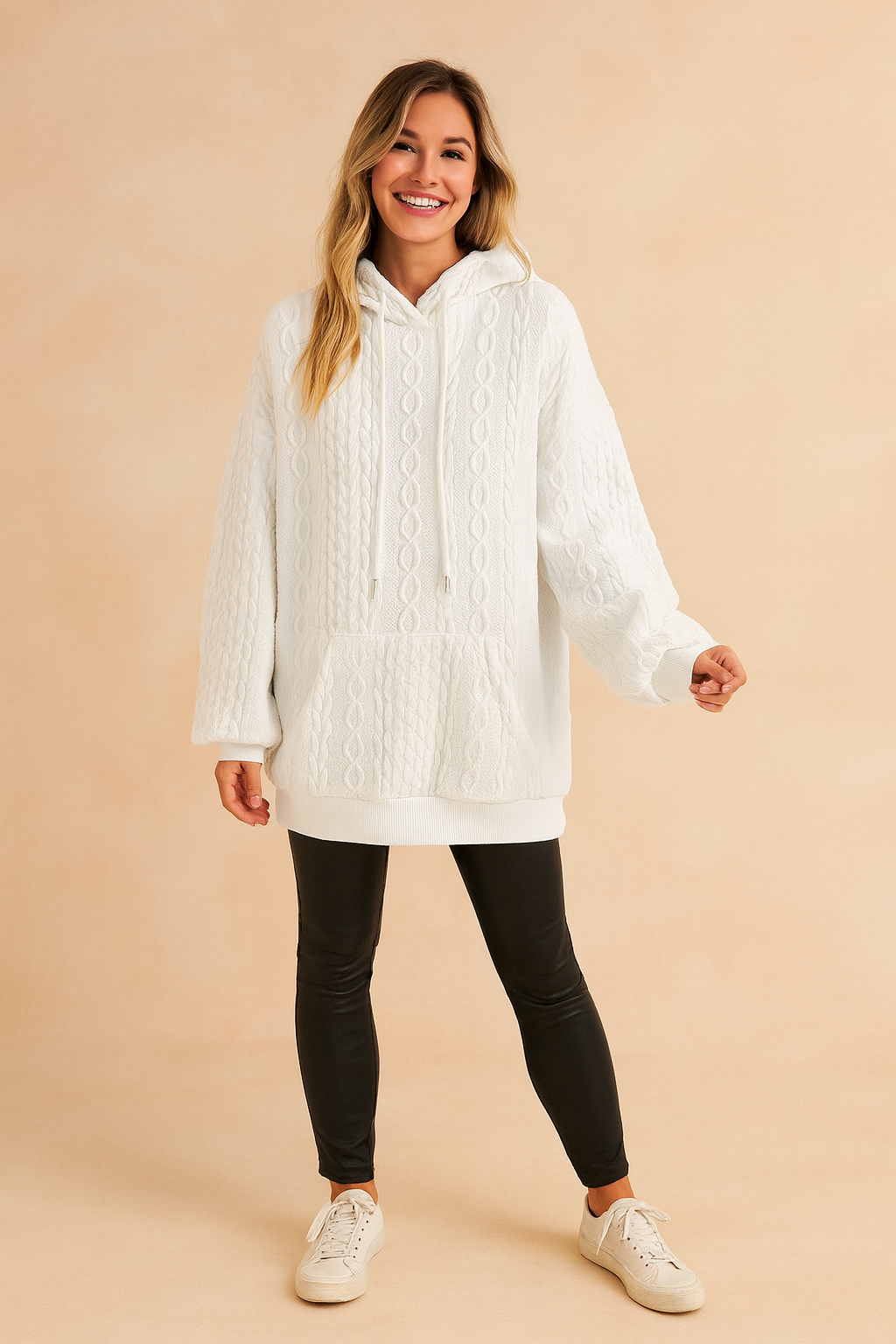 White cable knit hoodie with kangaroo pocket and drawstring, paired with black fitted pants and casual sneakers.