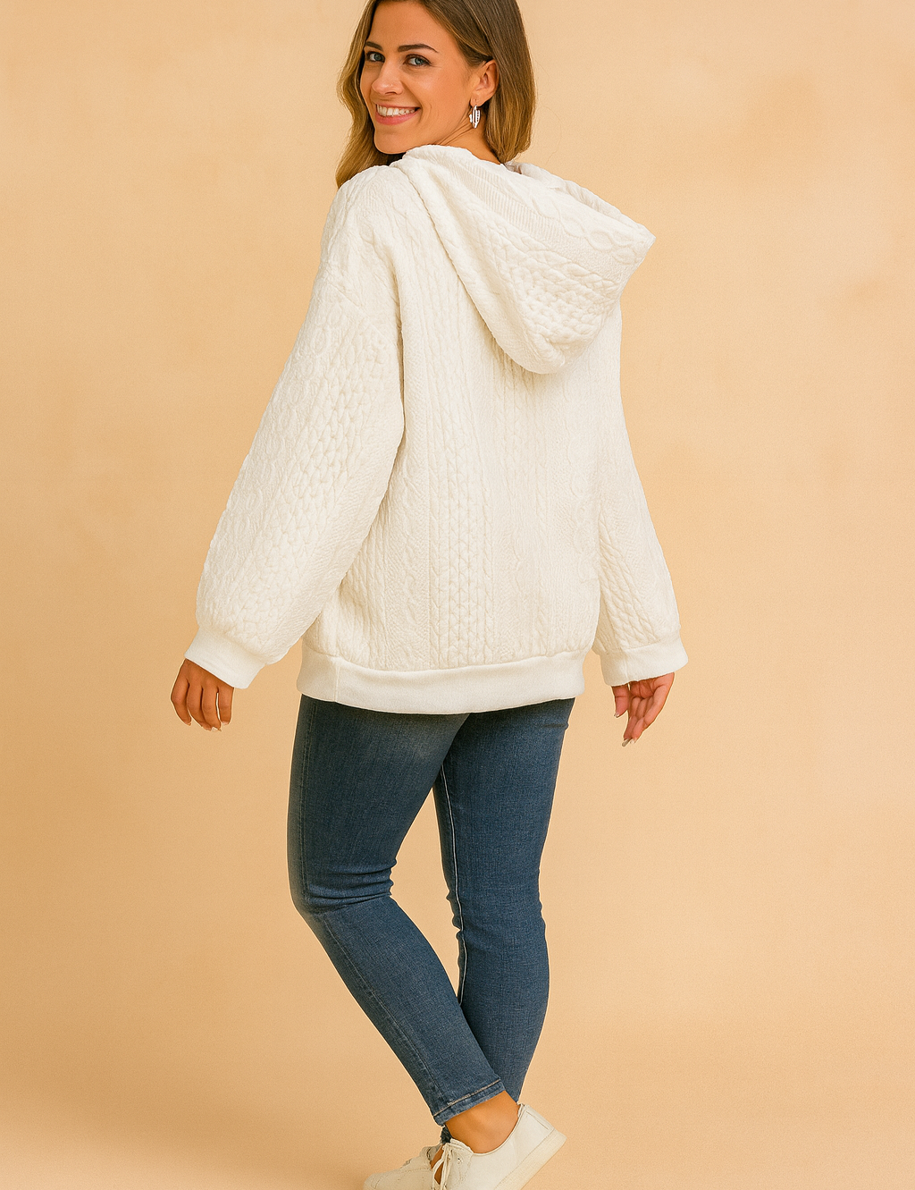 White cable knit hoodie with kangaroo pocket and drawstring, paired with black fitted pants and casual sneakers.