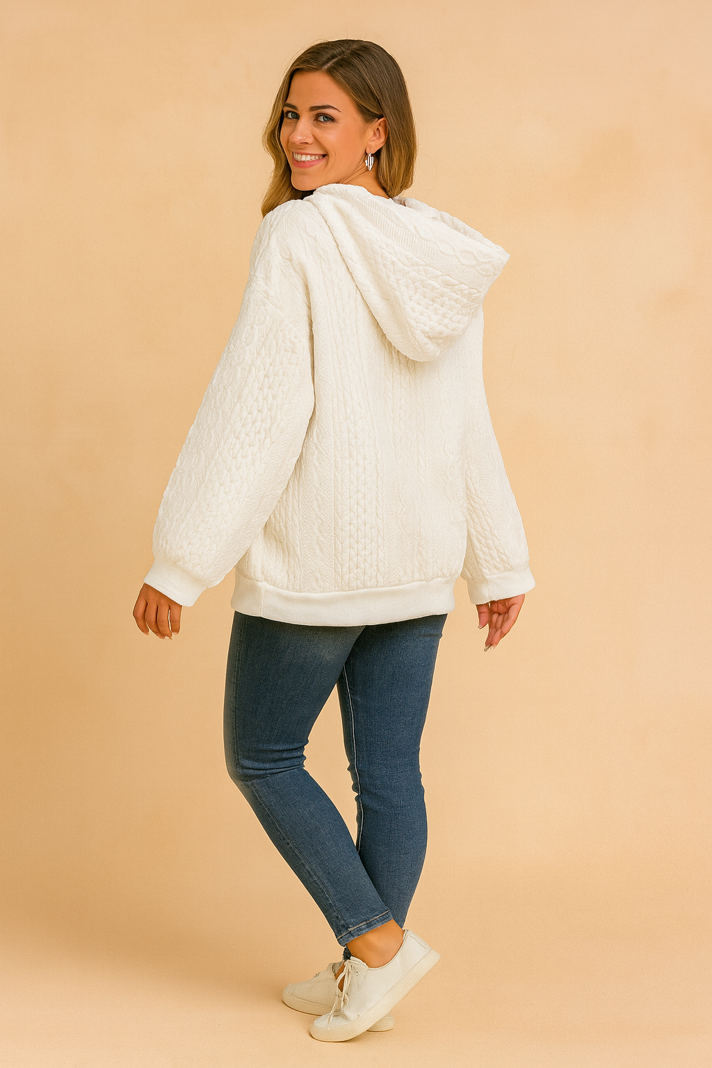 White cable knit hoodie with kangaroo pocket and drawstring, paired with black fitted pants and casual sneakers.