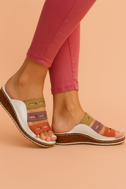 Women's open-toe sandals with multicolor leather straps in purple, orange, and yellow over a whie base, featuring visible stitching and cork wedge soles.