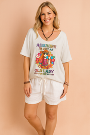 Loose-fit white T-shirt with colorful hippie-style graphic and bold text, paired with white drawstring shorts, perfect for a relaxed and playful summer look.
