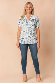 White v-neck blouse with short sleeves and navy botanical print, styled with fitted denim jeans and nude pointed heels.