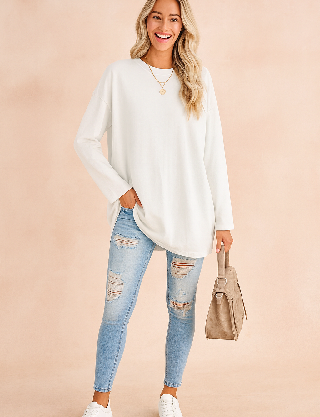 White oversized long-sleeve sweatshirt paired with light-wash distressed skinny jeans, complemented by white sneakers, a taupe handbag, and a gold pendant necklace.