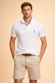 White short-sleeve polo shirt with classic collar, two-button placket, subtle embroidered chest logo, paired with beige chino shorts featuring a clean tailored fit and a brown braided belt.