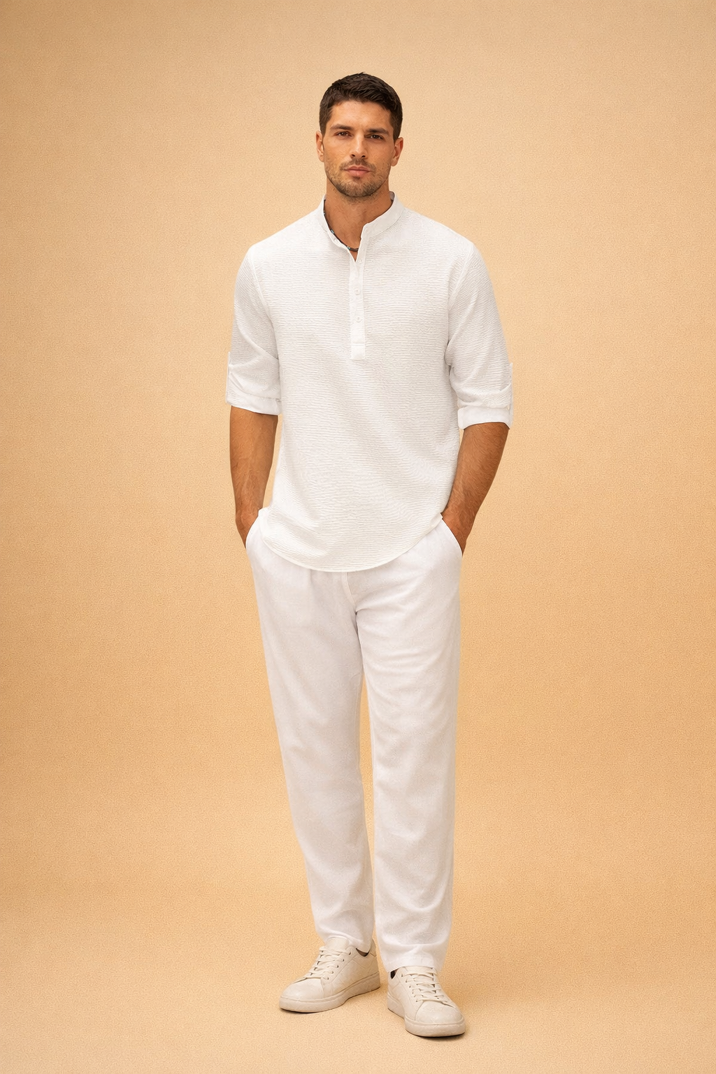 Textured white long-sleeve henley shirt with subtle woven fabric pattern, band collar and button placket, paired with relaxed-fit white trousers and clean minimalist white low-top sneakers for a refined summer casual look.