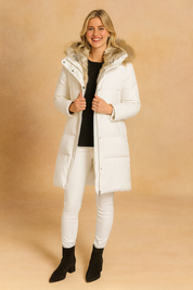 White padded winter jacket with fur-trimmed hood, front button closure, and longline design for cold-weather wear.