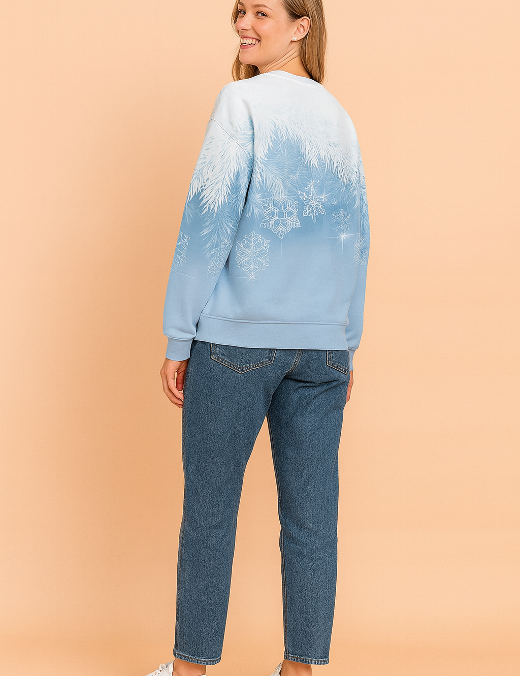 Light blue gradient sweatshirt with white frosted pine branch and snowflake print on the back, paired with mid-wash straight-leg jeans and white lace-up sneakers.