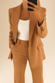 Camel brown tailored blazer with peak lapels and matching high-waisted trousers, paired with a fitted white tank top in a minimalist business casual style.
