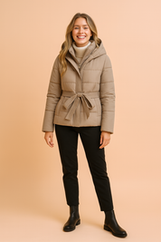 Women’s beige short hooded puffer jacket with waist belt, front zipper, and quilted design, offering a warm and stylish winter outerwear option.