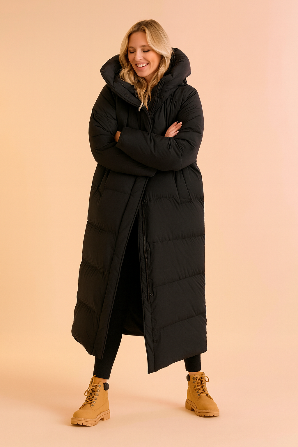 Women's long black puffer down jacket with oversized hood, quilted padding, full-length design, button-up closure, side pockets, paired with black leggings and tan lace-up boots