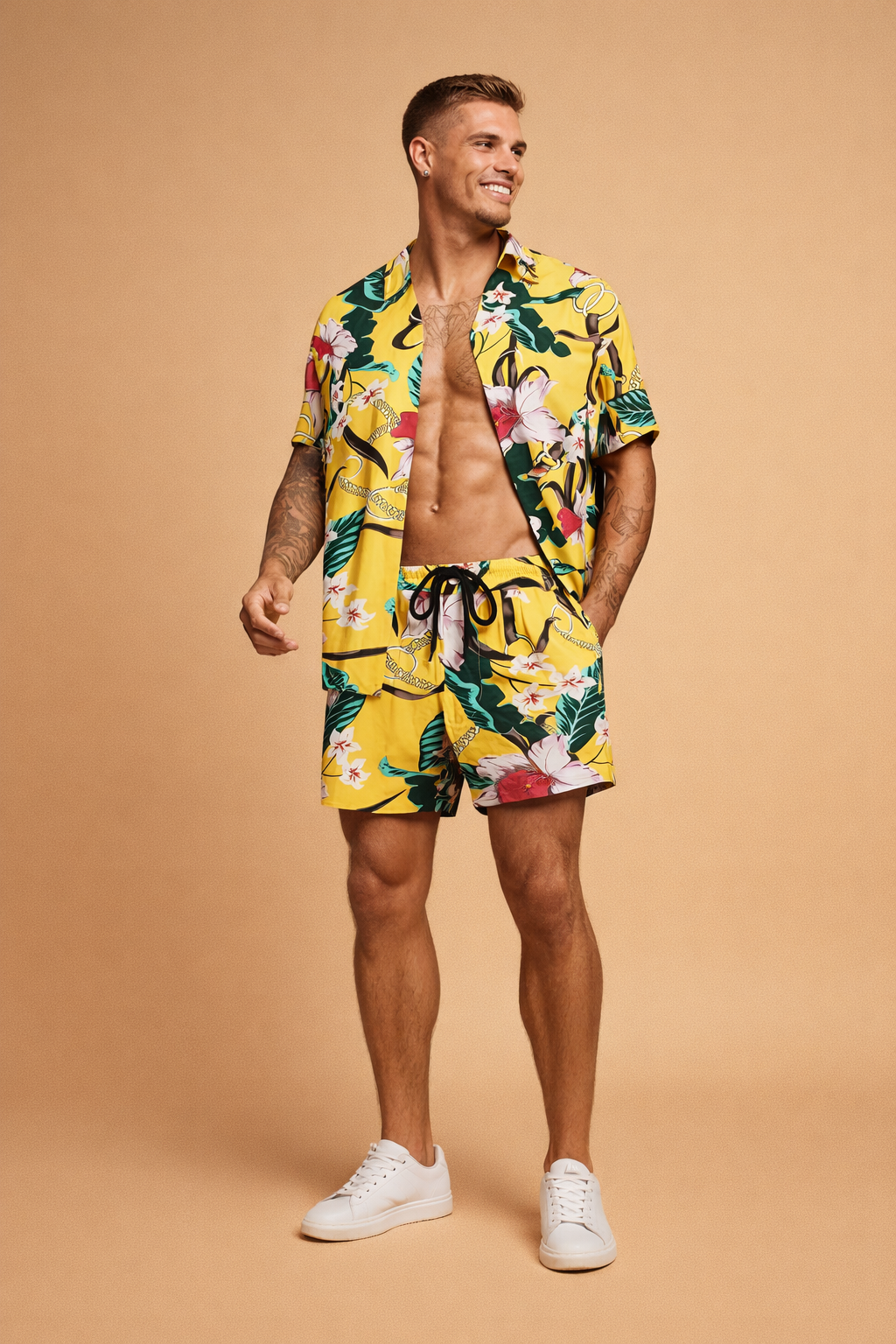 Yellow tropical print short-sleeve button-up shirt with matching drawstring shorts featuring bold floral and leaf motifs in green, white, pink, and black, styled as a coordinated summer set with a relaxed tailored fit and lightweight fabric drape, paired with clean minimalist footwear for a polished resort look