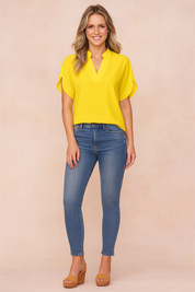 Women's casual outfit featuring a short-sleeve emerald green V-neck blouse paired with high-rise blue skinny jeans.